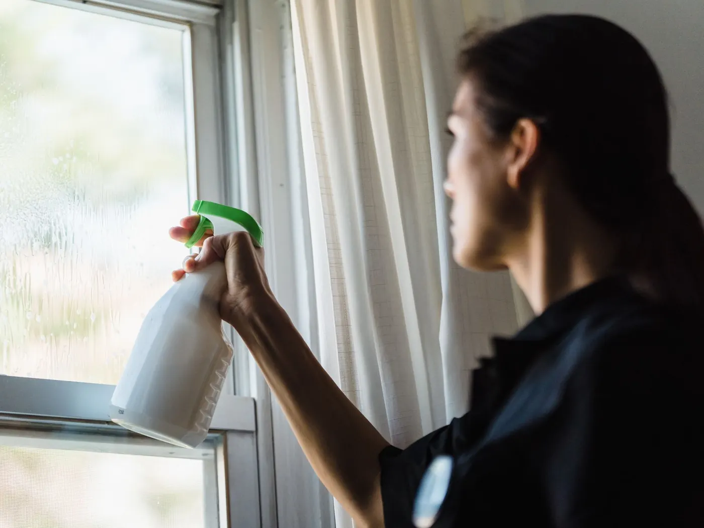 Schoonmaker brengt reinigingsmiddel aan op een raam